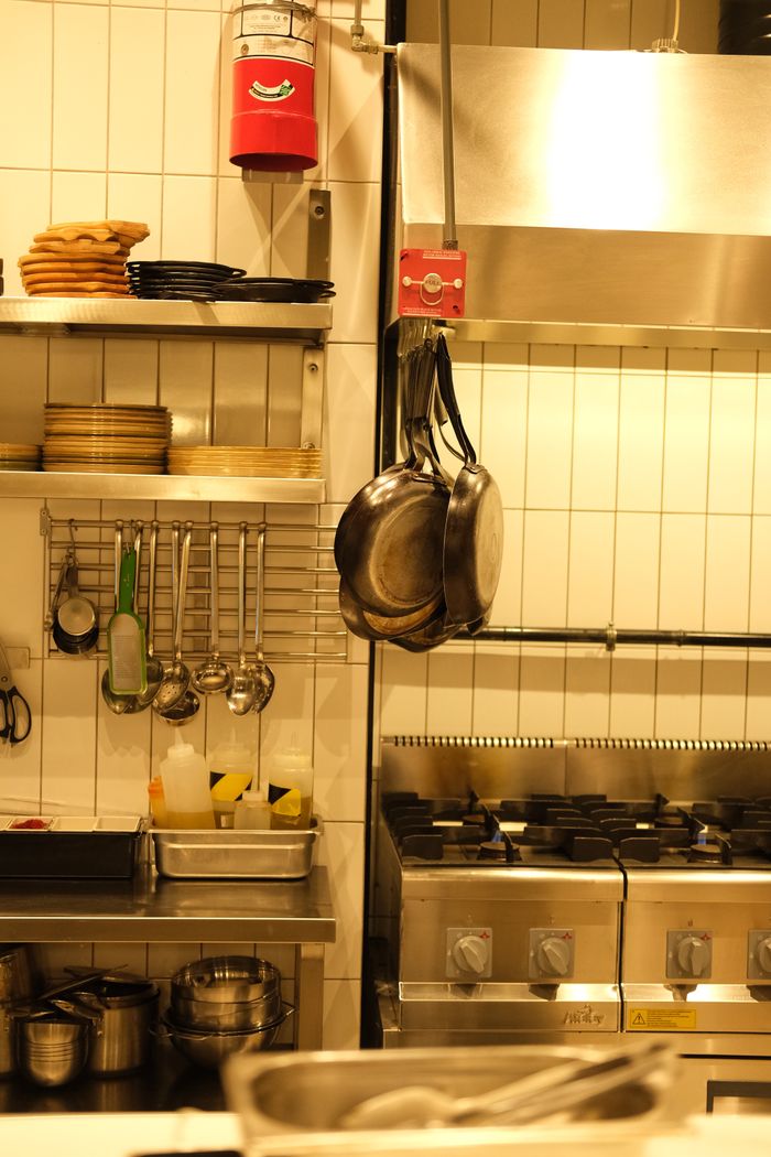 A well-equipped industrial kitchen with hanging pans and cooking utensils.